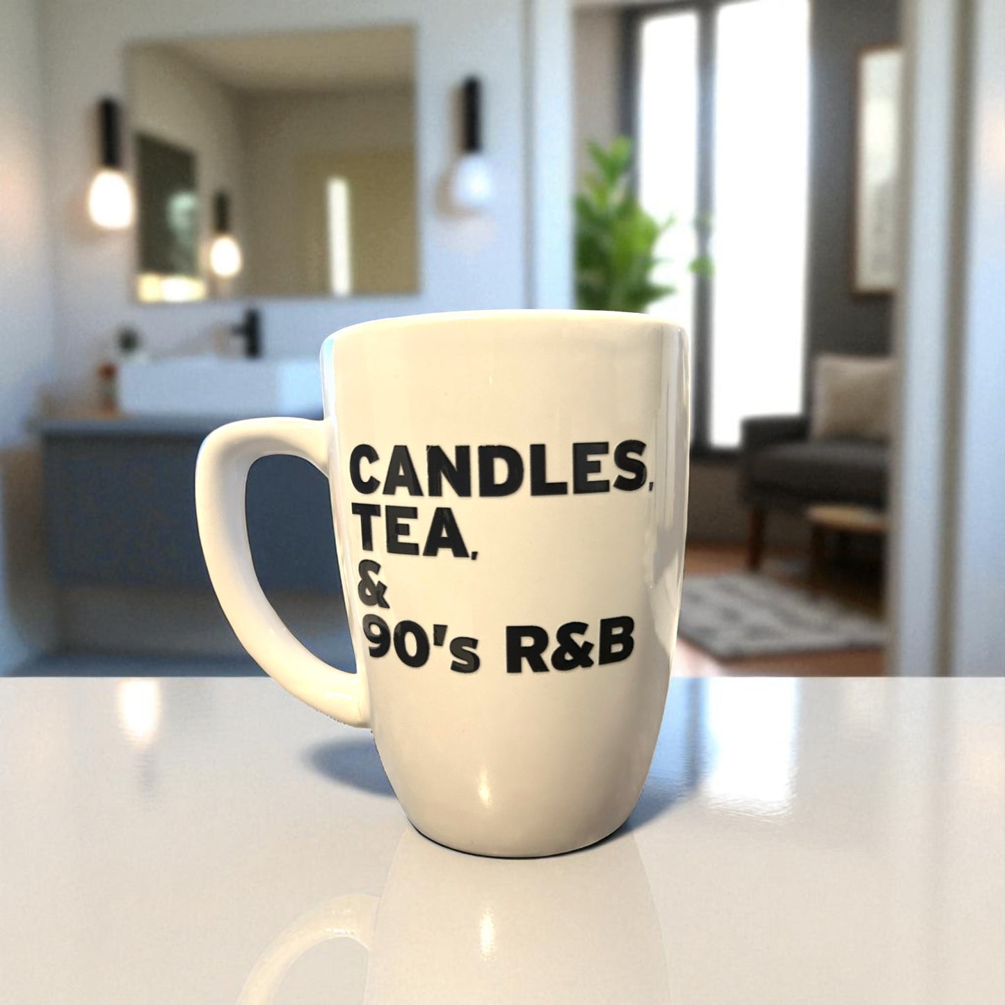 White mug with text 'CANDLES, TEA, & 90's R&B' on a kitchen counter.