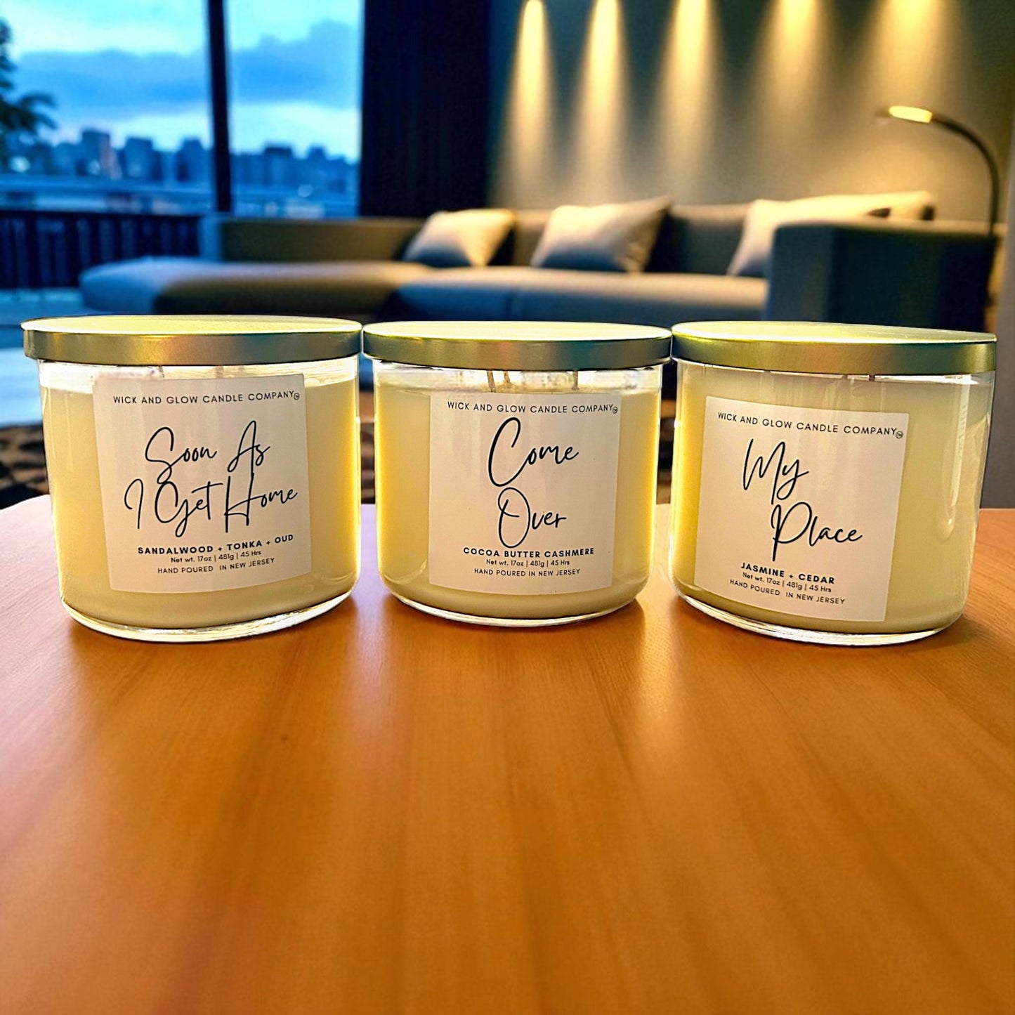 Three candles with labels on a wooden surface, with a blurred indoor background