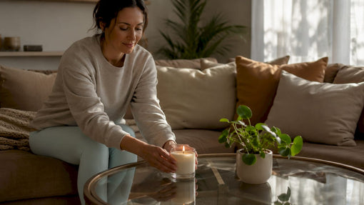 Woman placing lit soy wax candle in kitchen