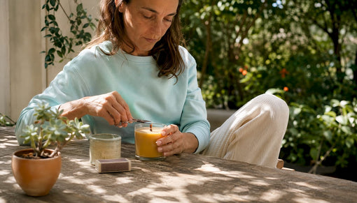Woman trimming wooden wick candle at table