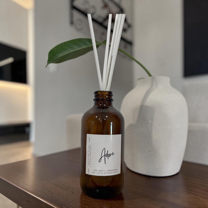 Brown diffuser bottle with white sticks and a label on a wooden surface.