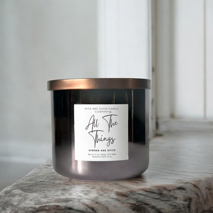 Wick and Glow's luxury soy wax candle in a gray glass container on a marble table. The scent is Ginger and spice.