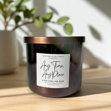 Large luxury soy wax candle with a label on a wooden surface with a plant in the background