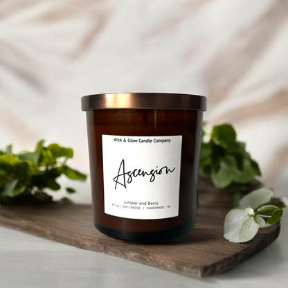 Amber glass jar candle with bronze lid labeled 'Ascension', offering a juniper and berry aroma