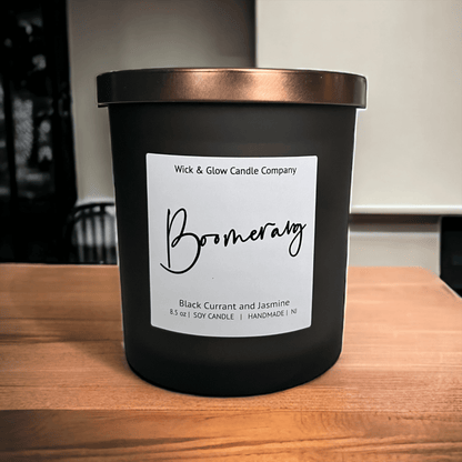 Wick and Glow's luxury soy wax candle in a black glass container with a bronze lid and white label on a wooden table 