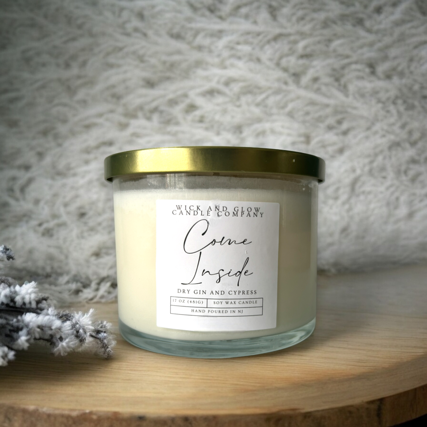 Clear two wick candle in a large jar on a wooden table with a white label from Wick and Glow Candles