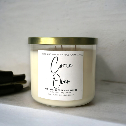 A large candle in a clear jar with a white label from Wick and Glow Candles. The scent is Cocoa Butter Cashmere