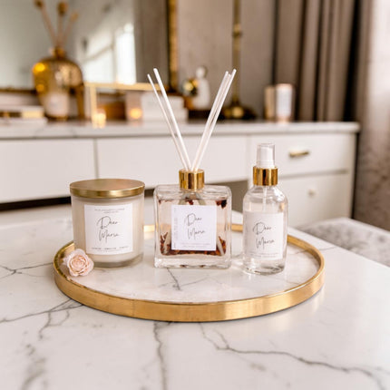 Decorative items including a candle, diffuser, and bottle on a marble surface with a blurred background.