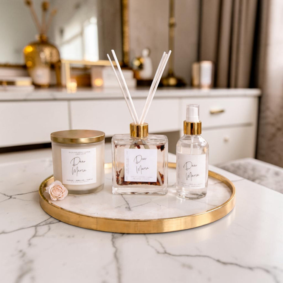 Decorative items including a candle, diffuser, and bottle on a marble surface with a blurred background.