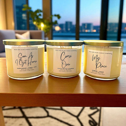 Three candles from Wick & Glow Candle Company on a wooden surface with a cityscape in the background.
