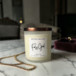 Candle labeled 'Feels Good' by Wick & Glow Candle Company on a marble surface with a blurred background.