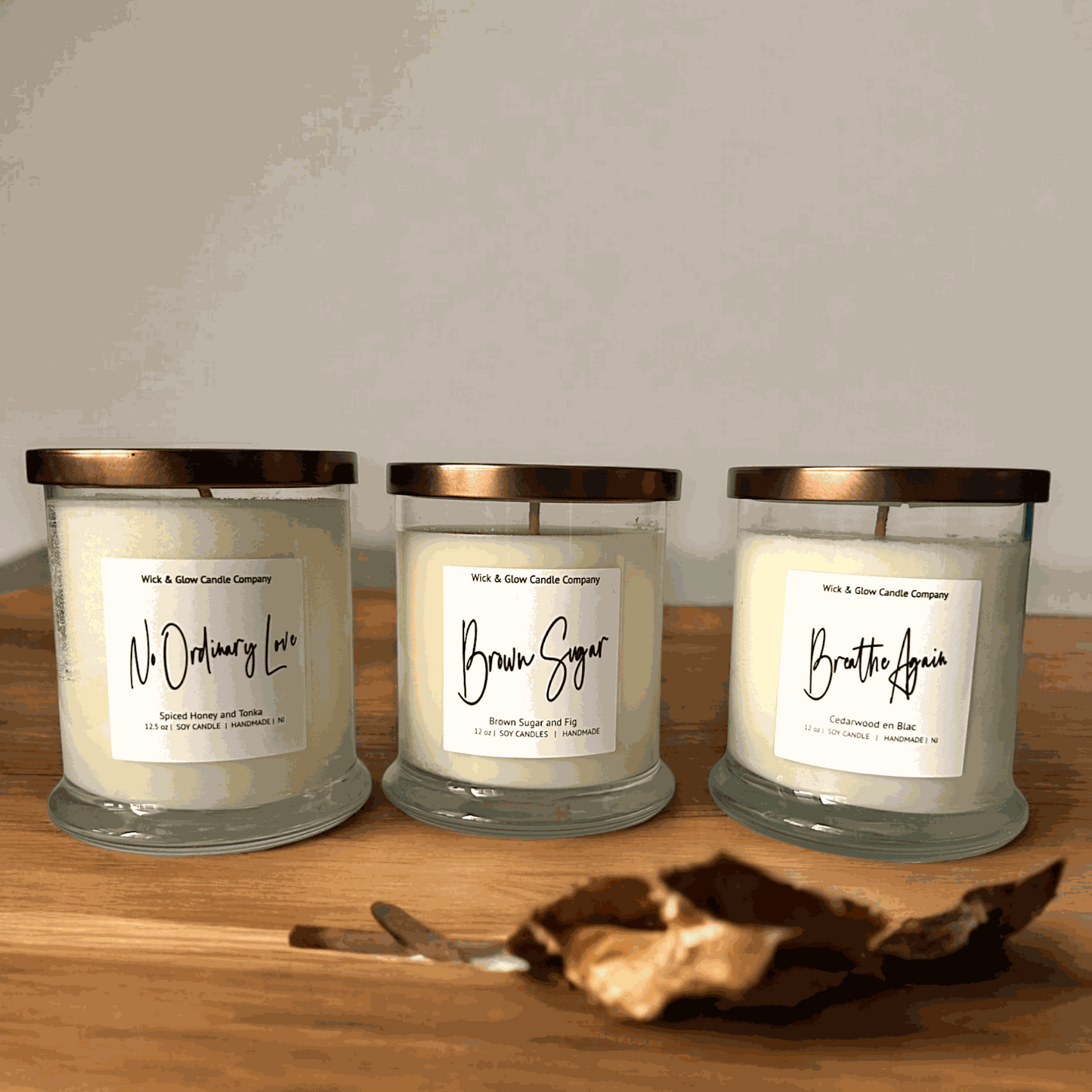 3  candles in clear jars with gold lids and white labels from Wick and Glow Candle Company with a white background. Scents are Brown Sugar and fig, Cedarwood and Spiced Honey