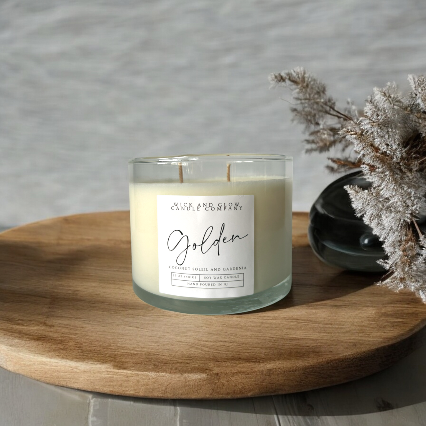 Clear two wick candle in a large jar on a wooden table with a white label from Wick and Glow Candles