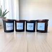 Four black candles with labels on a wooden surface