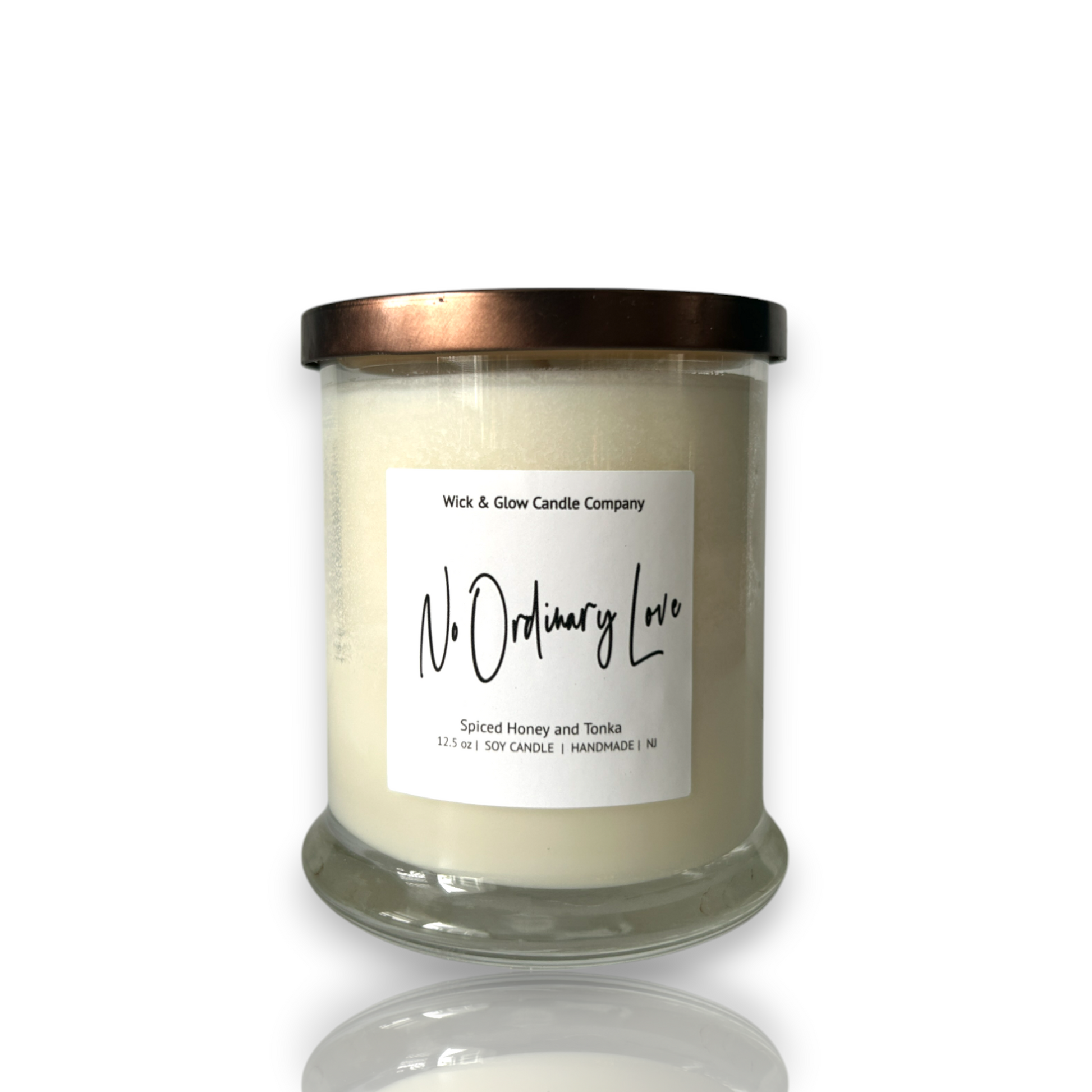 White candle in a clear jar with a bronze lid on a white background. The scent is spiced honey and tonka