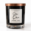 A soy wax candle in a clear glass jar with a metallic copper lid and a white label reading 'Wick and Glow Candle Company' and 'Slow Down Cashmere + Musk'.