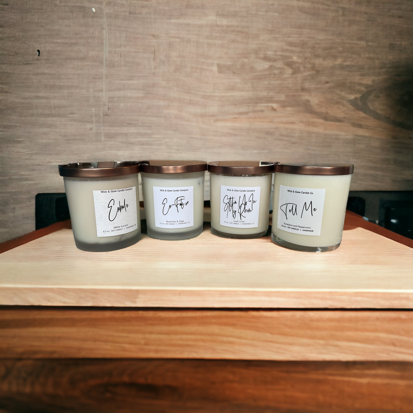 4 candles in white jars with bronze lids on a wood surface