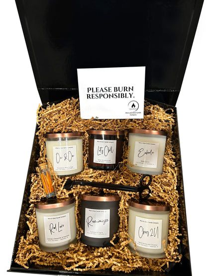 Welcome Home Box black gift box with six candles in black and white glass jars and a wick cutter and matches in brown craft paper on a white background