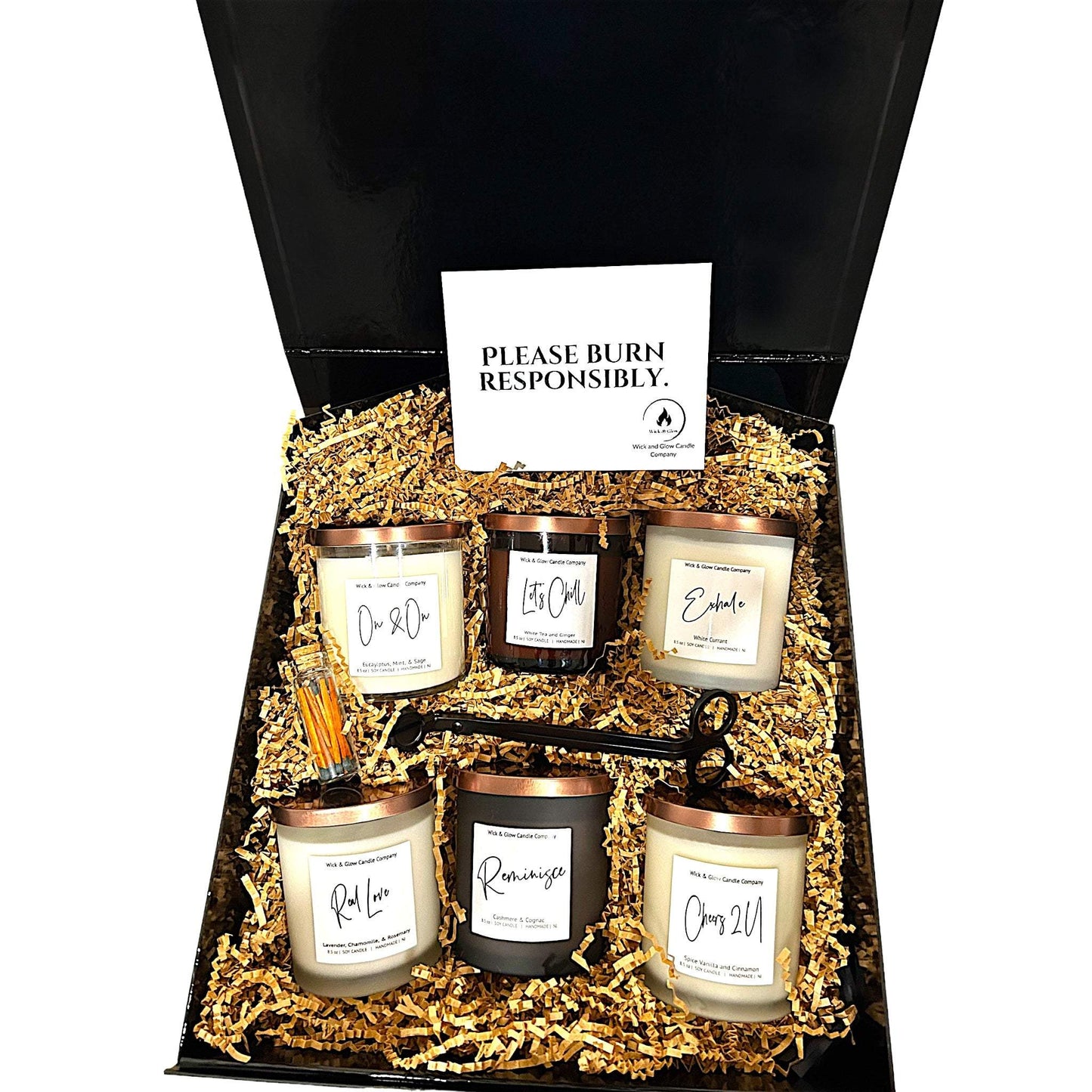 Welcome Home Box black gift box with six candles in black and white glass jars and a wick cutter and matches in brown craft paper on a white